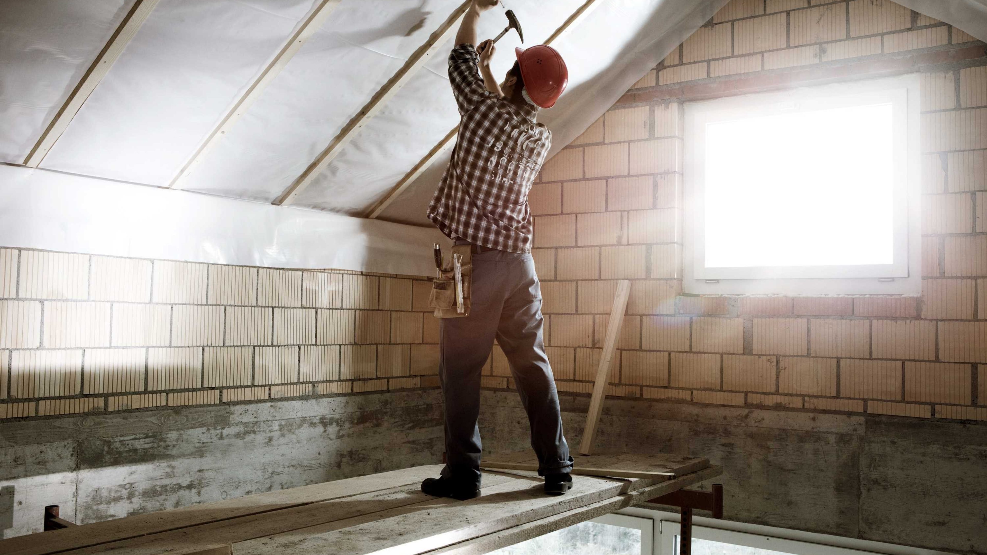 Un homme entreprend des travaux de rénovation sur le toit de son logement.
