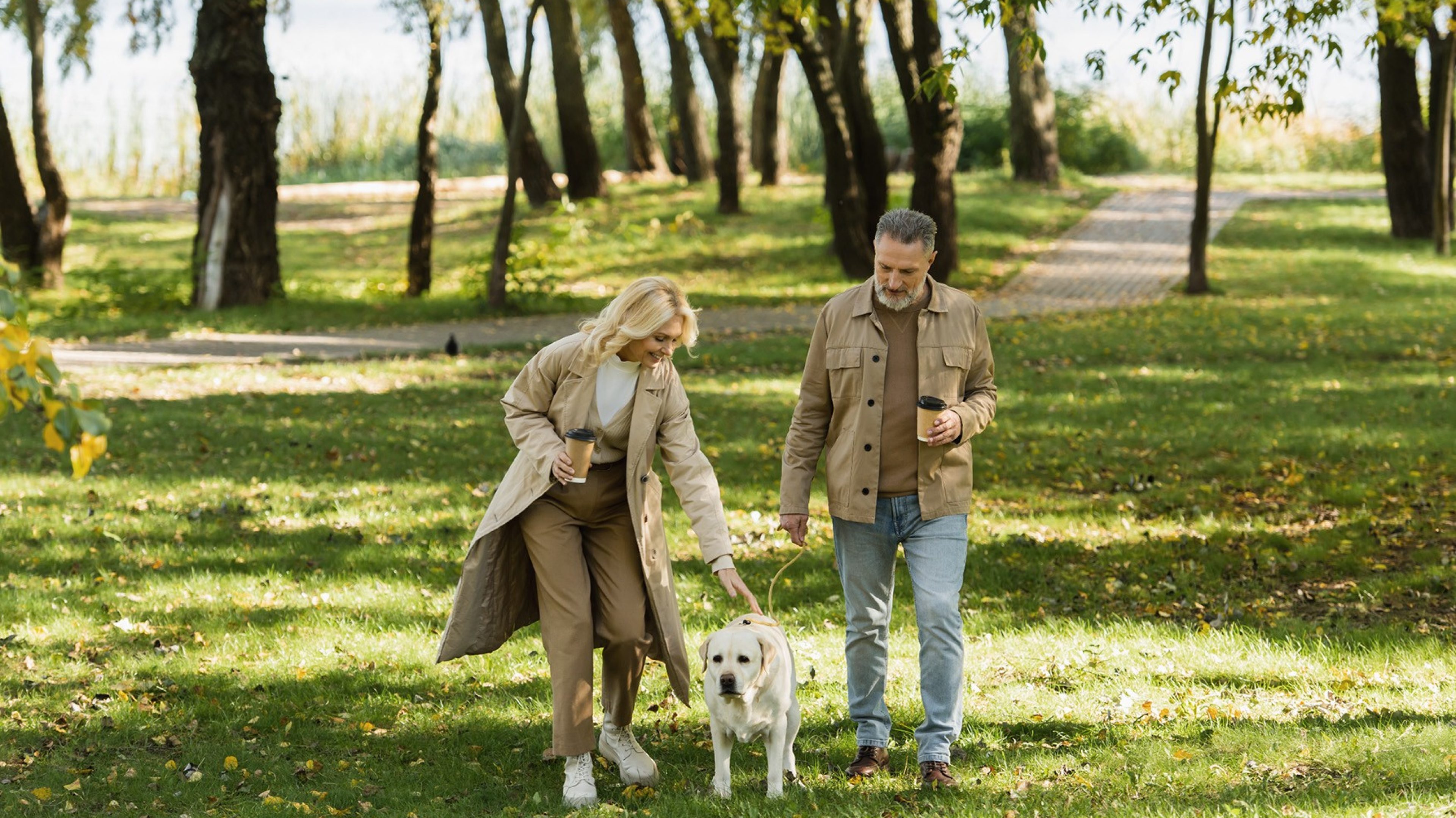 Zwei Personen spazieren mit ihrem Hund im Wald mit ihrem Hund.