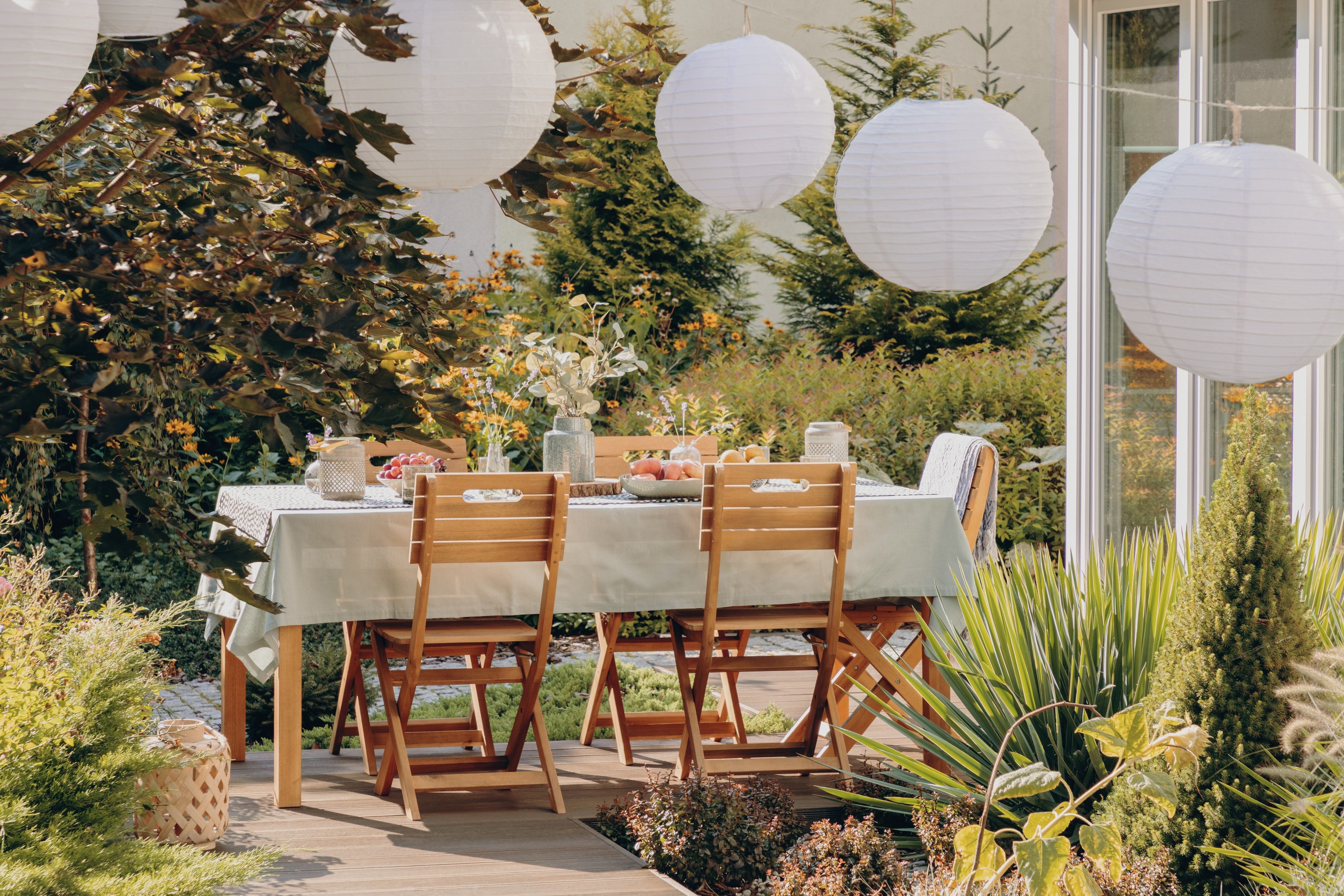 Real photo of round lamps above a table with wooden chairs in a garden