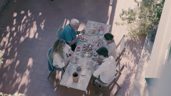 Vier Personen sitzen auf der Terrasse und geniessen ein Essen.