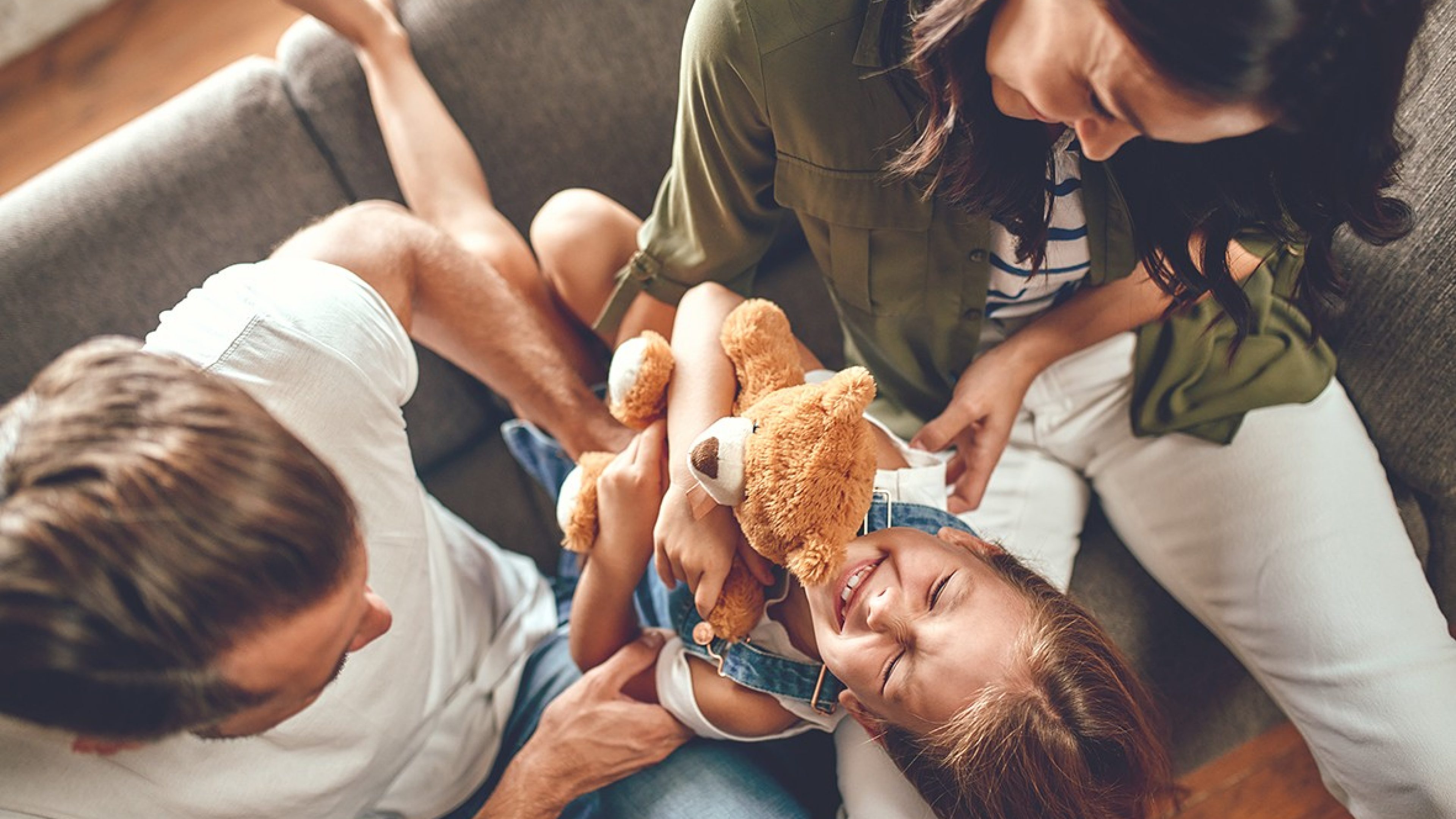 Die Eltern spielen mit der Tochter auf dem Sofa.