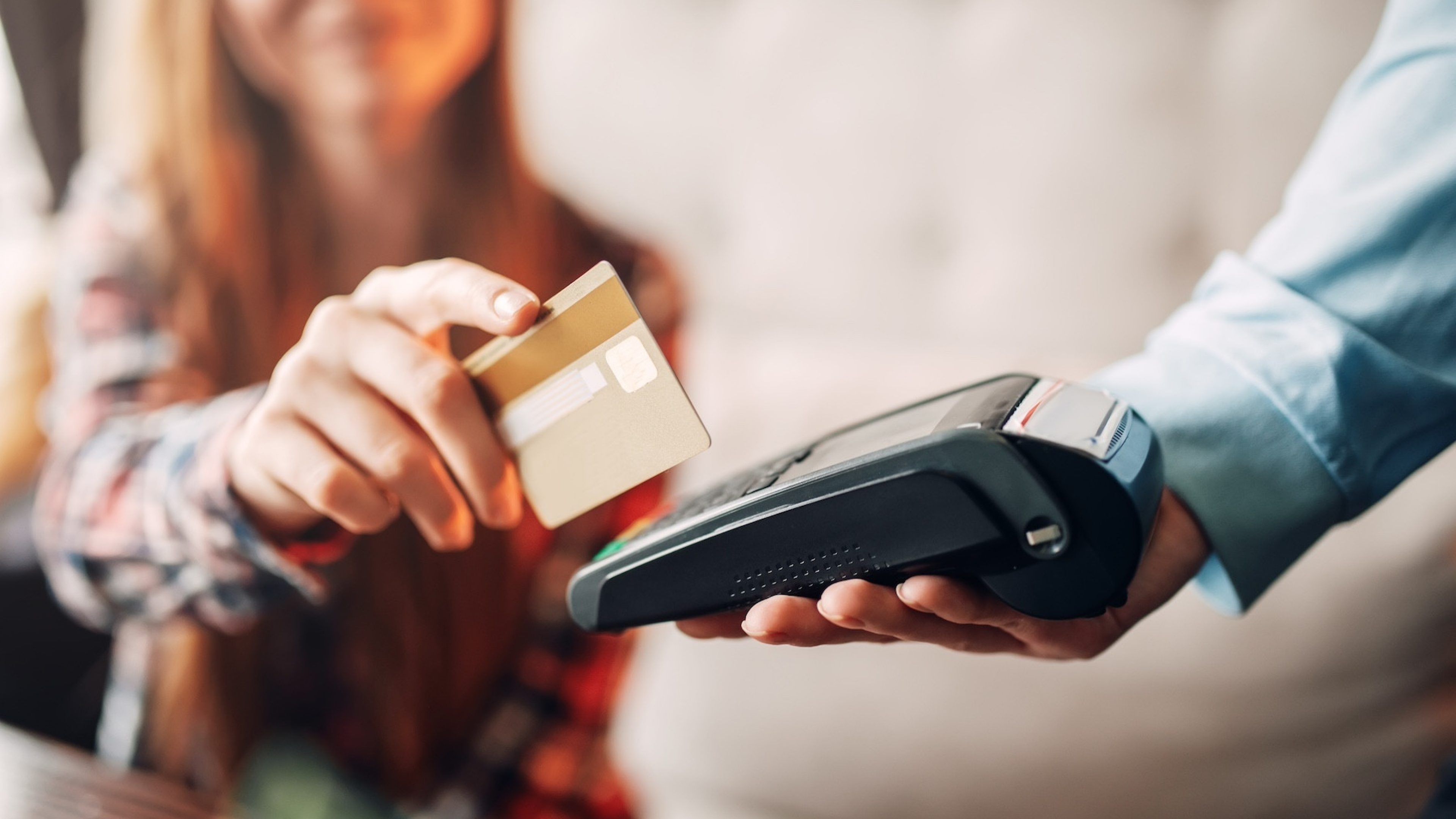 Young woman paying with credit card in cafe, waiters hand with terminal. Modern payment technologies