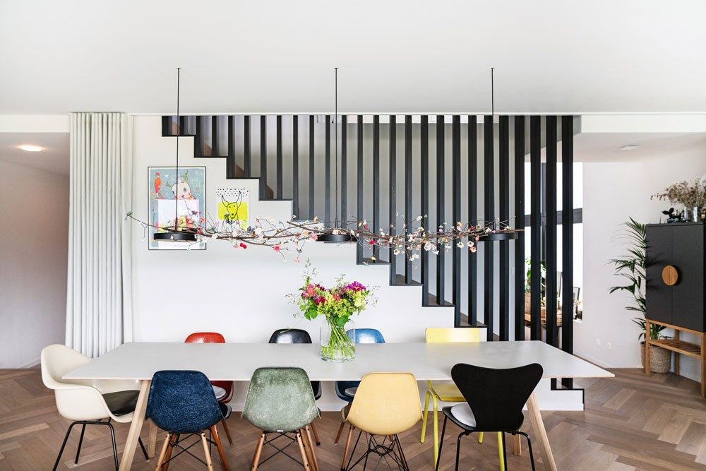 Ein langer Tisch in einem Wohnraum, um ihn herum stehen elegante Eames Chairs von Vitra.