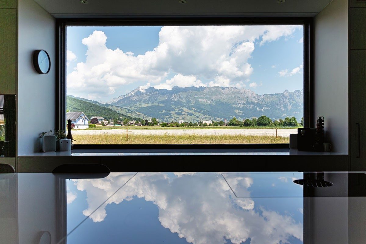 Ein Fenster in einer Küche, aus dem man auf eine Bergkulisse schaut.