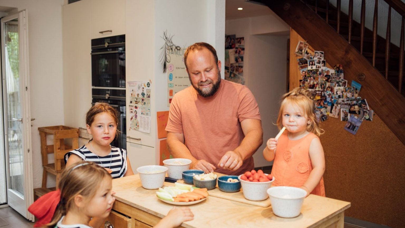 Vater bereitet gemeinsam mit drei Kindern das Essen vor. 