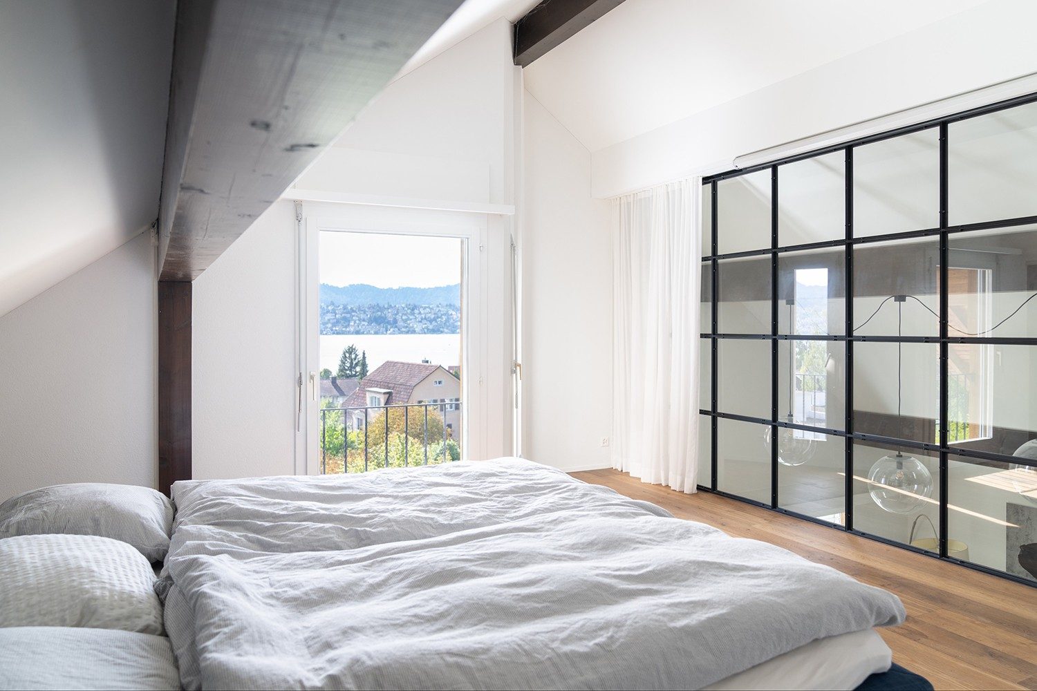 Das Bett steht vor einer grossen Glasfront und man hat Aussicht auf den Zürisee