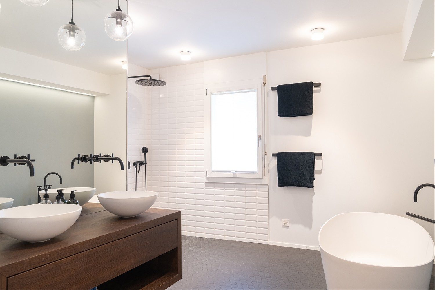 Das Badezimmer ist im schlichten Weiss und Schwarz gehalten, mit einem schönen Holzdetail