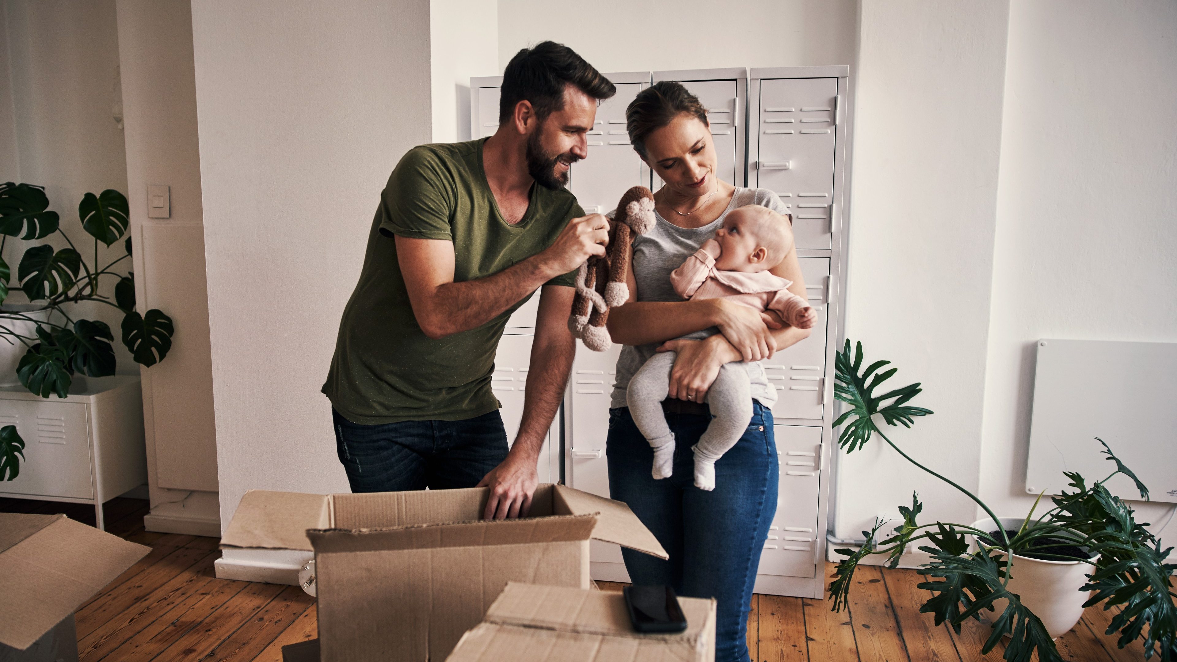 Cropped shot of an affectionate young father showing his young baby girl a stuffed toy while opening boxes in their new home on moving day