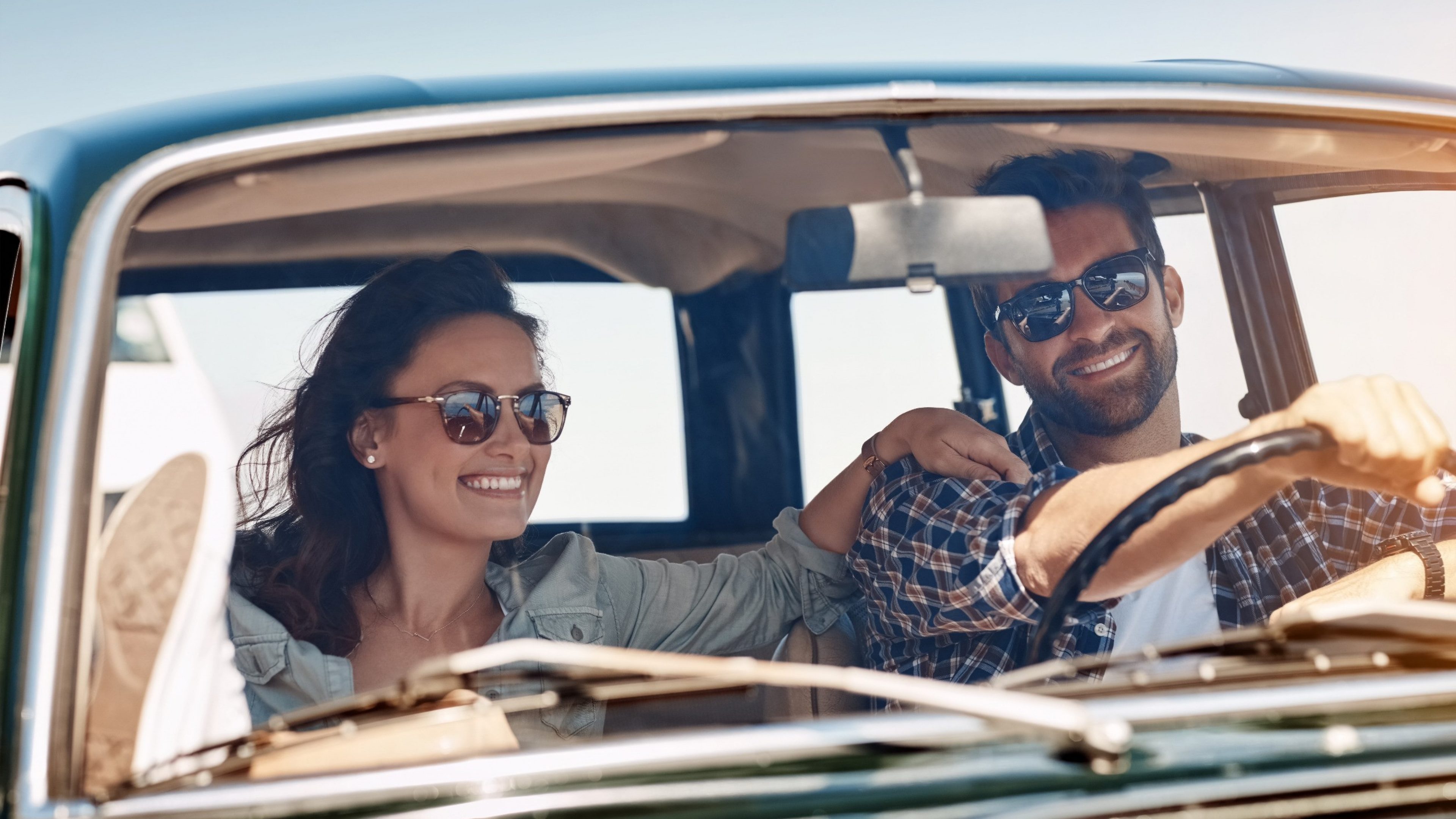 Girl with curly hair leaning on the door of her convertible with dog