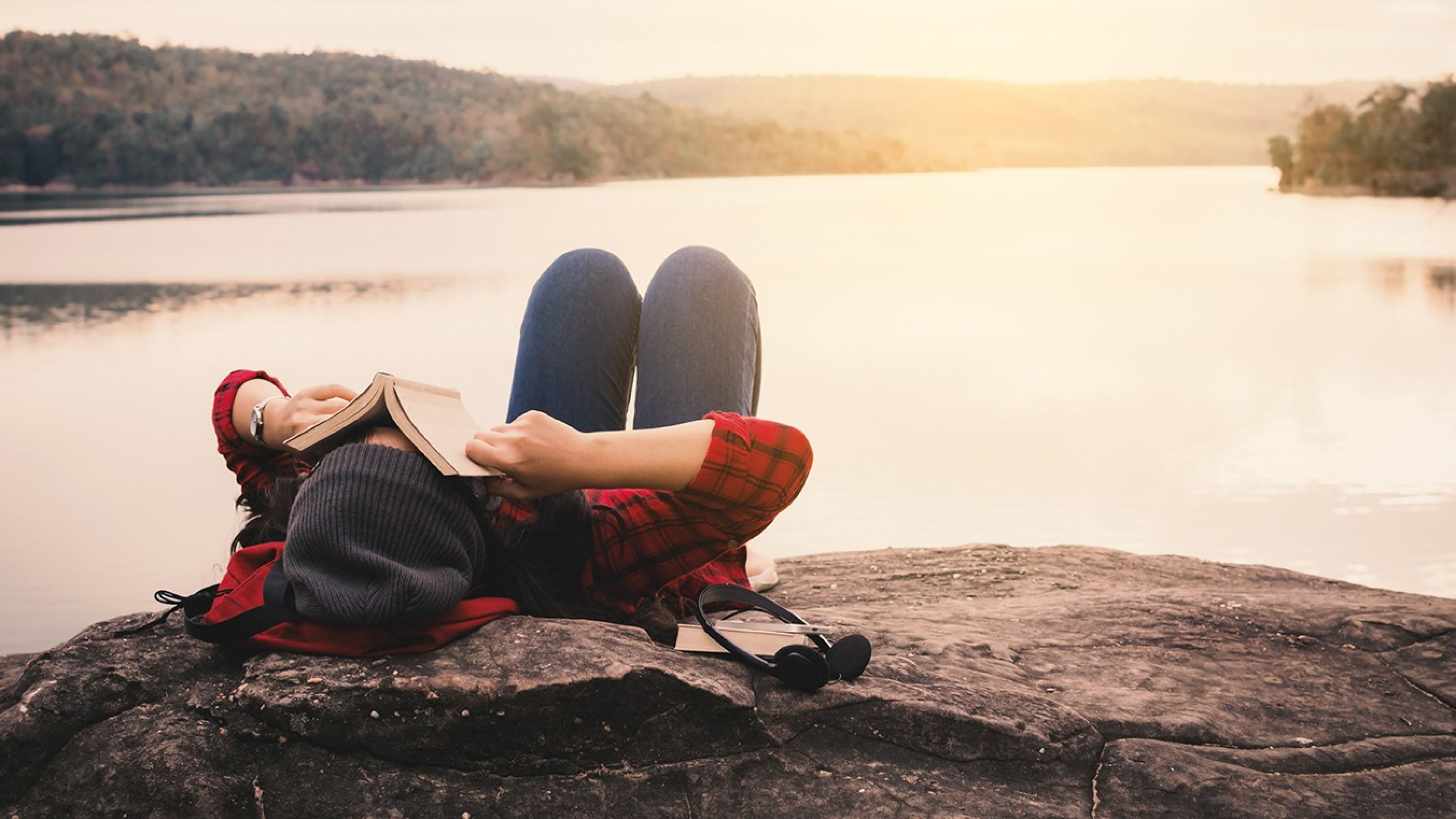 Relaxing moment Asian tourist reading a book on rock ,enjoying time on holiday concept ,color of vintage tone