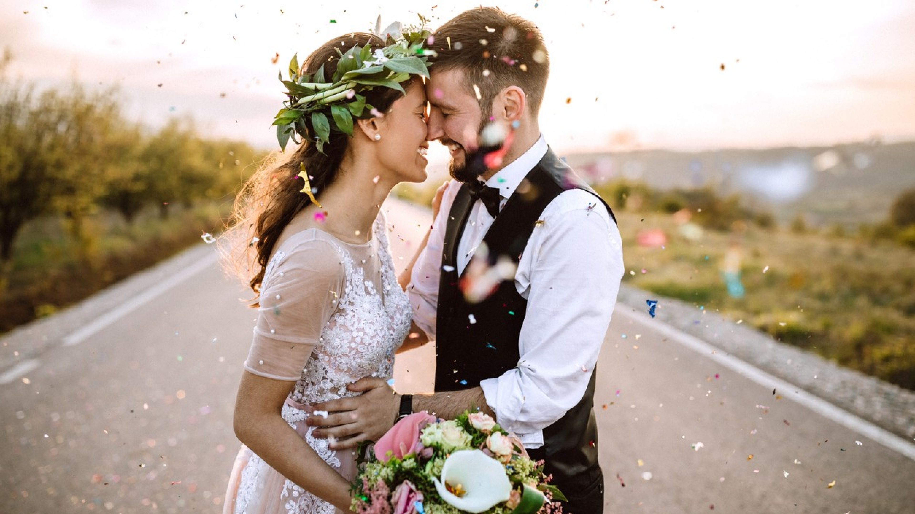 Un couple d’amoureux, elle en robe de mariée et lui en costume, sont dans la rue. Des confettis sont jetés dans les airs.