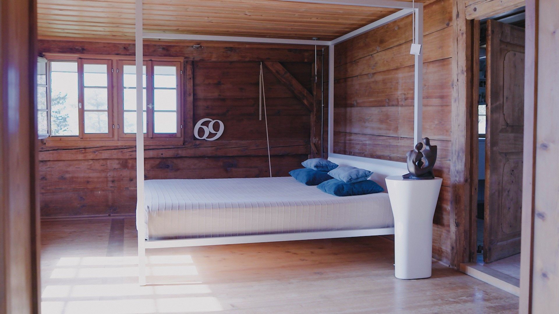 Un lit à baldaquin trône dans une chambre habillée de murs en bois.