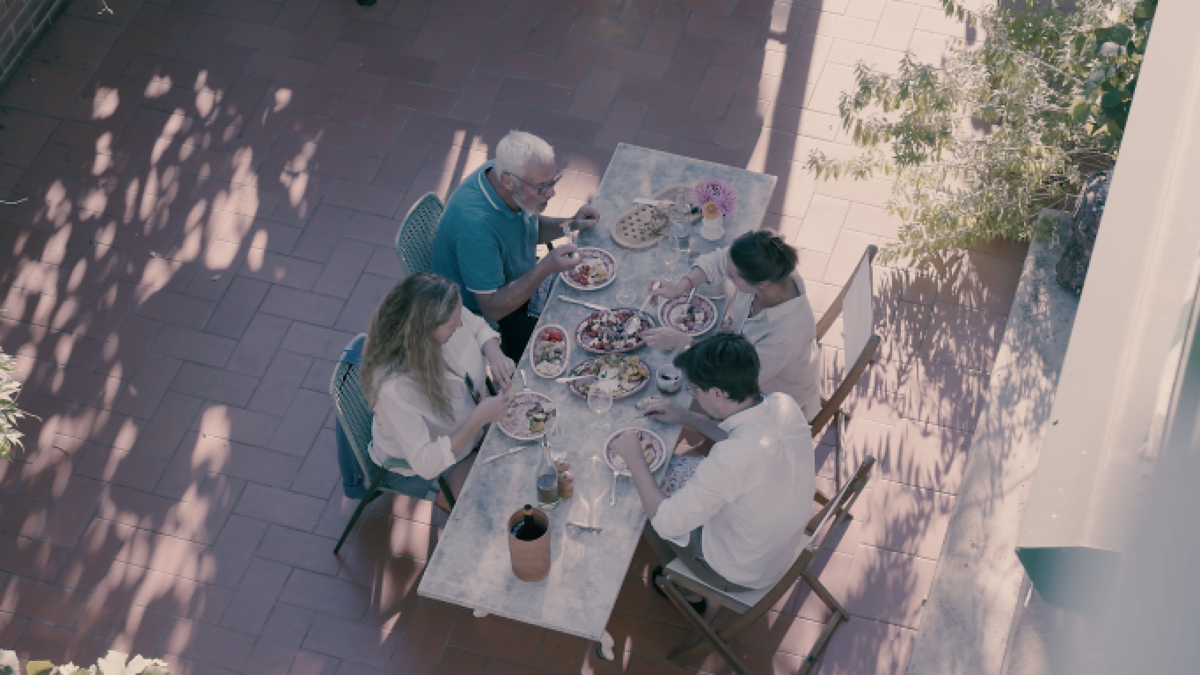 Quatre personnes sont assises sur la terrasse et savourent un repas.