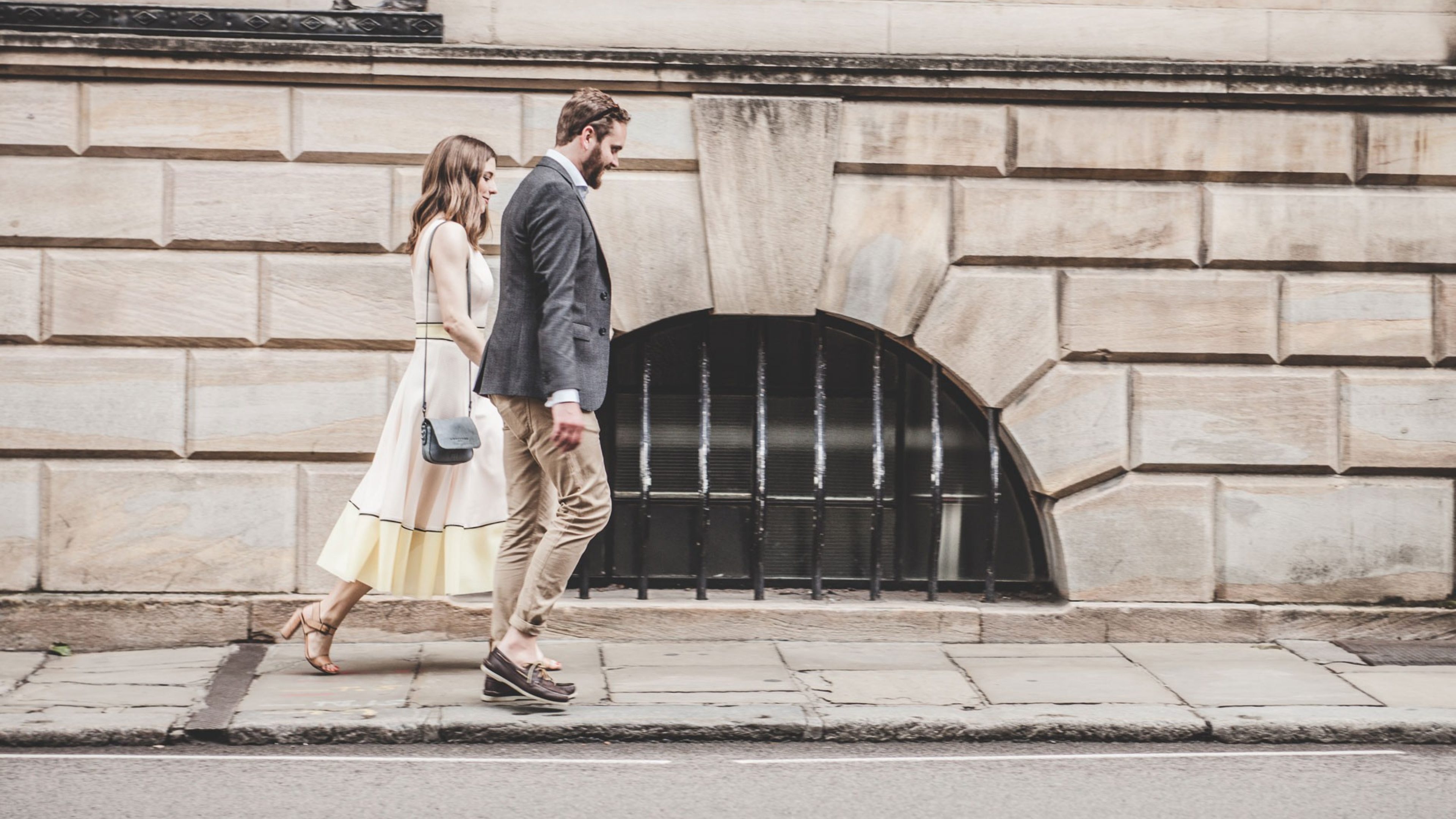 Un couple se tenant la main sur le trottoir devant un bâtiment