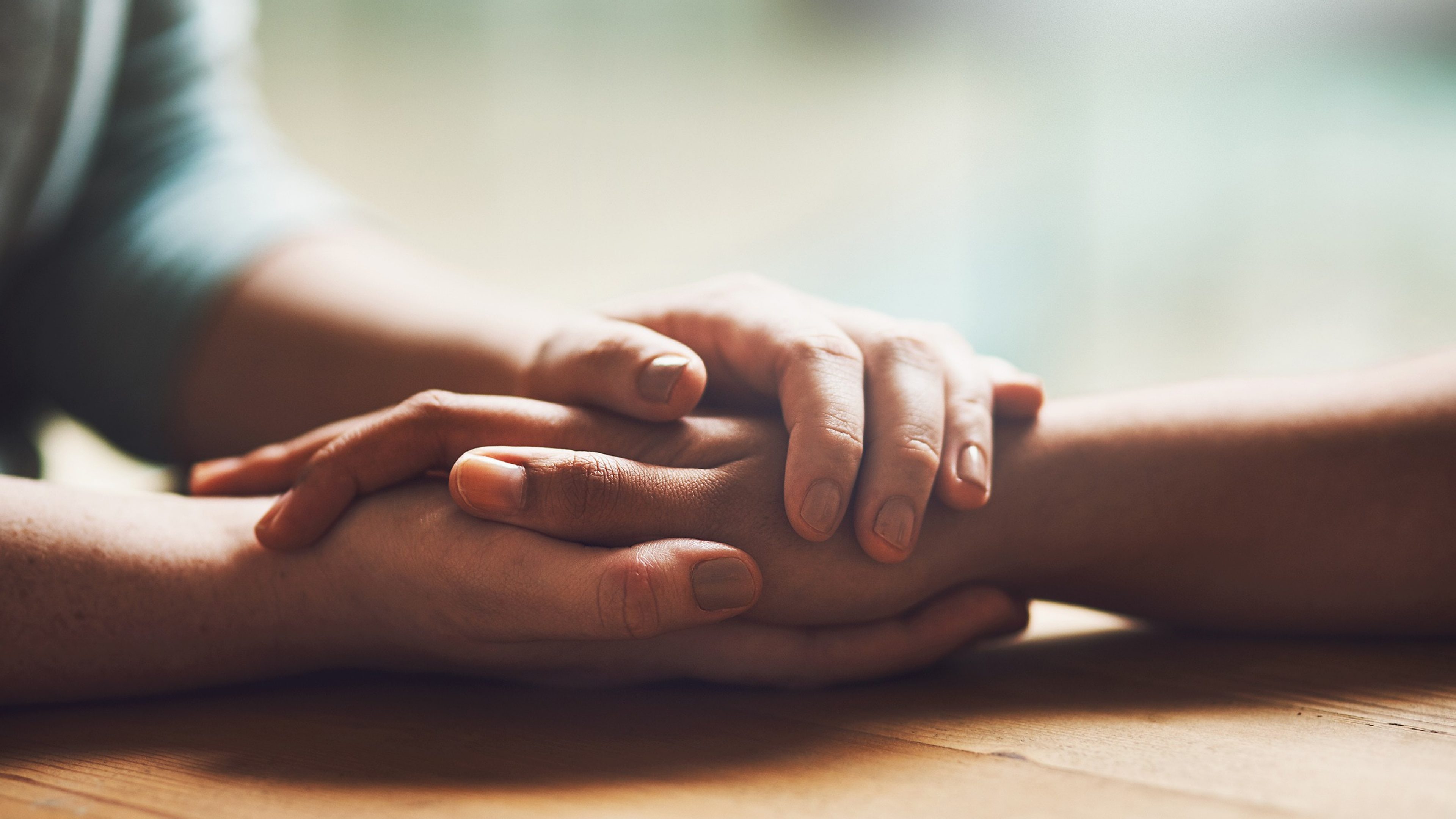 Une infirmière tient les mains d’une patiente.