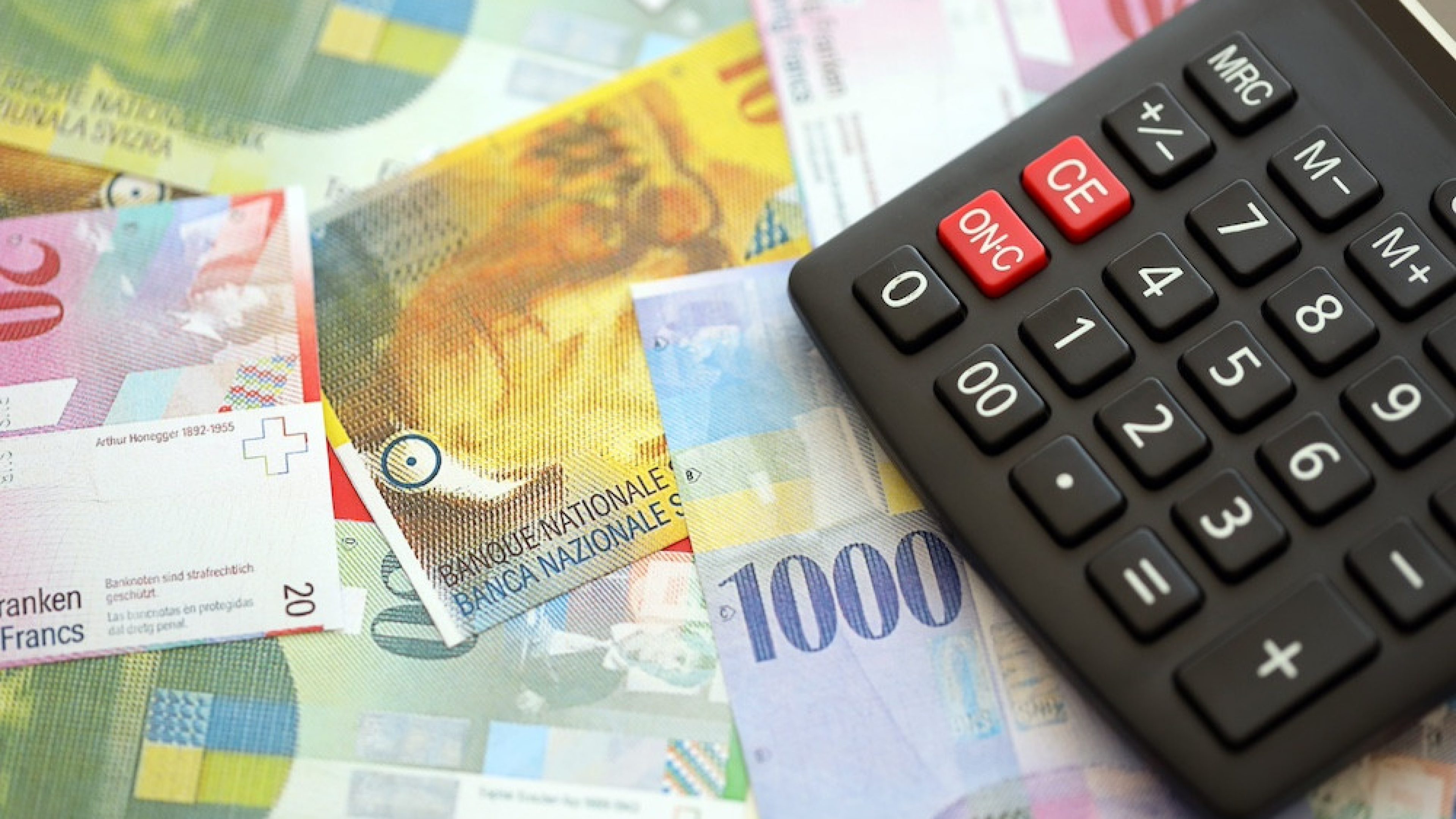 Swiss franc banknotes and calculator. The current francs money bills and calc lies on table in big amount. The concept of taxation and money count in Switzerland