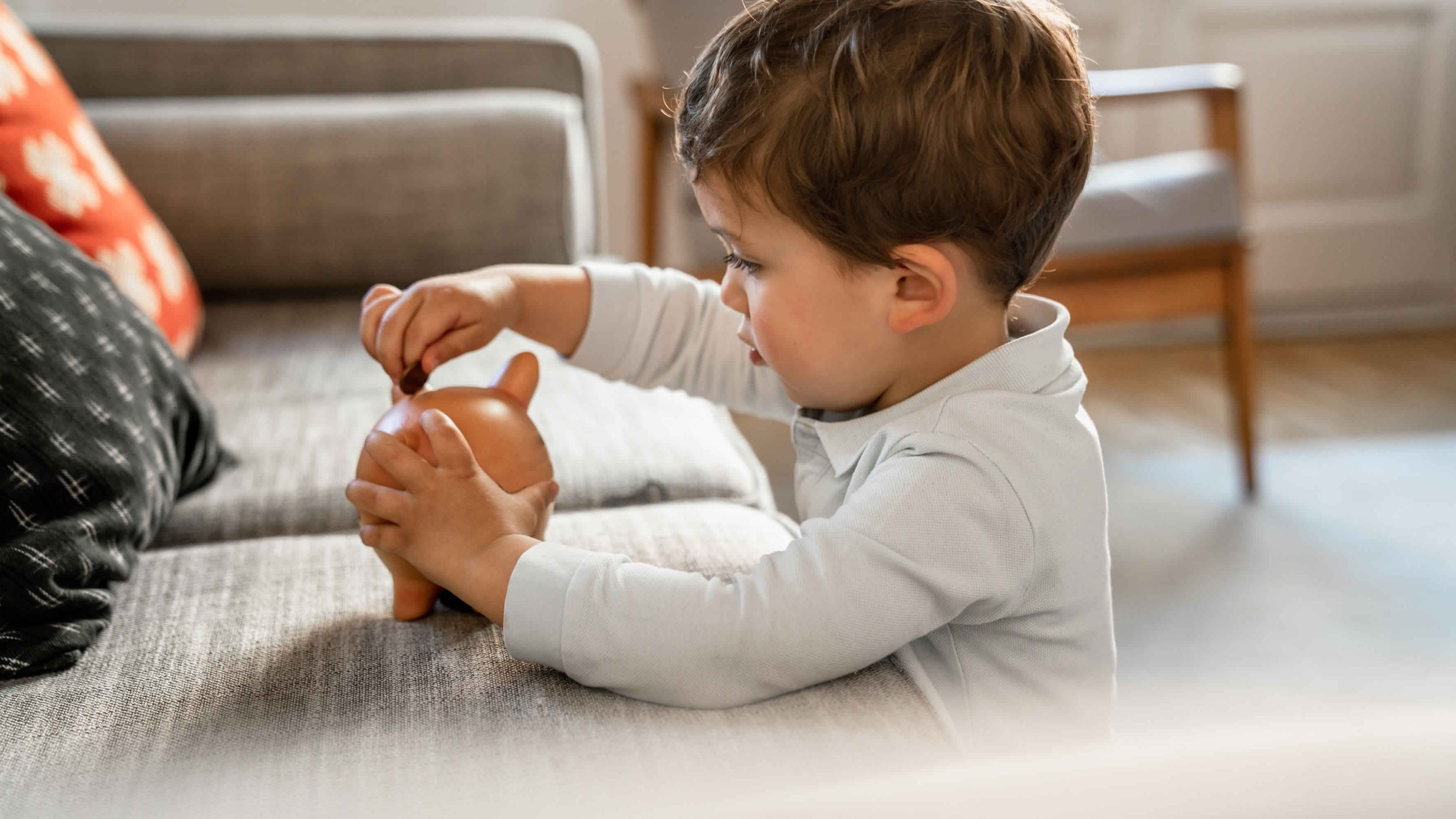 Boy putting coins on piggy bank