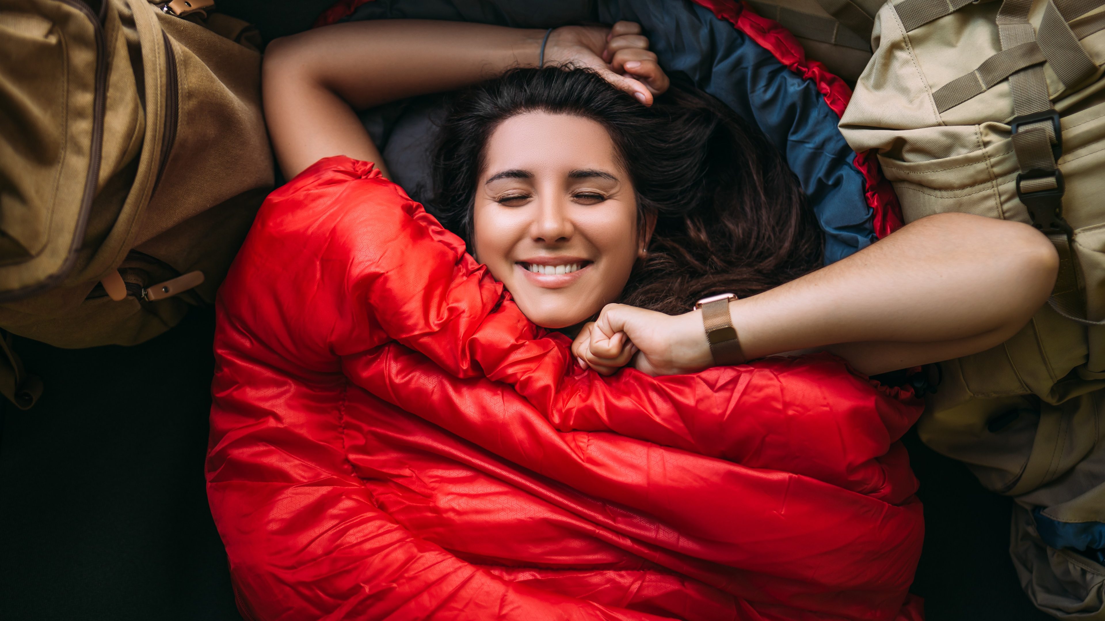 The traveler is resting in a sleeping bag. Rest concept. A tourist is resting in a tent. Woman relaxing in sleeping bag. Travel, camping concept, adventure. Happy smiling female traveler. The Traveler