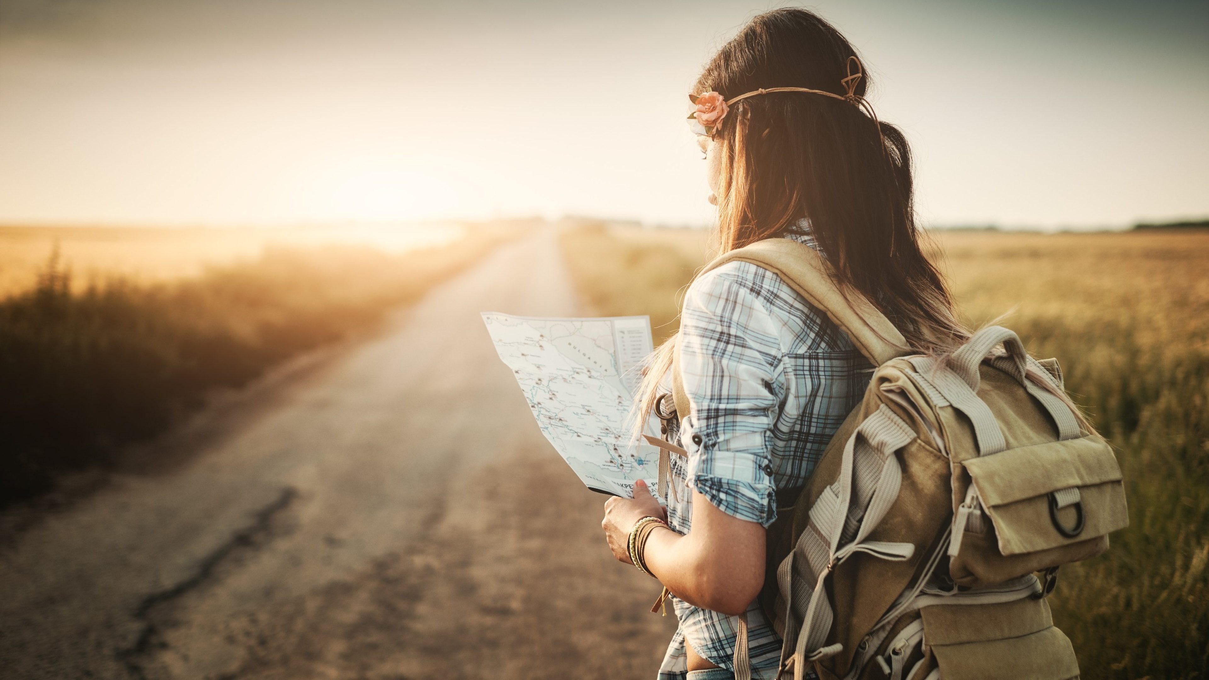 Jeune femme regardant une carte et portant un sac à dos.