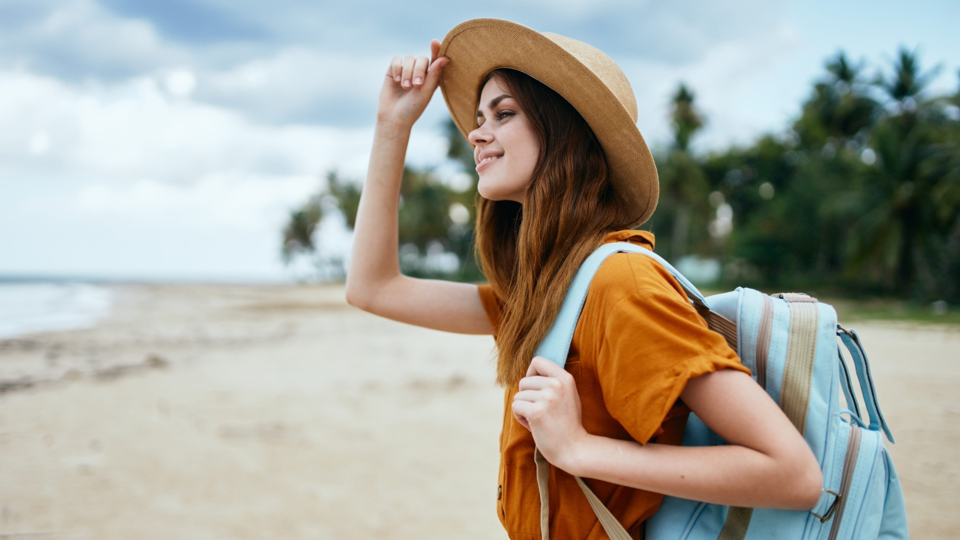 woman travels on the beach near the sea with a backpack on her back. High quality photo