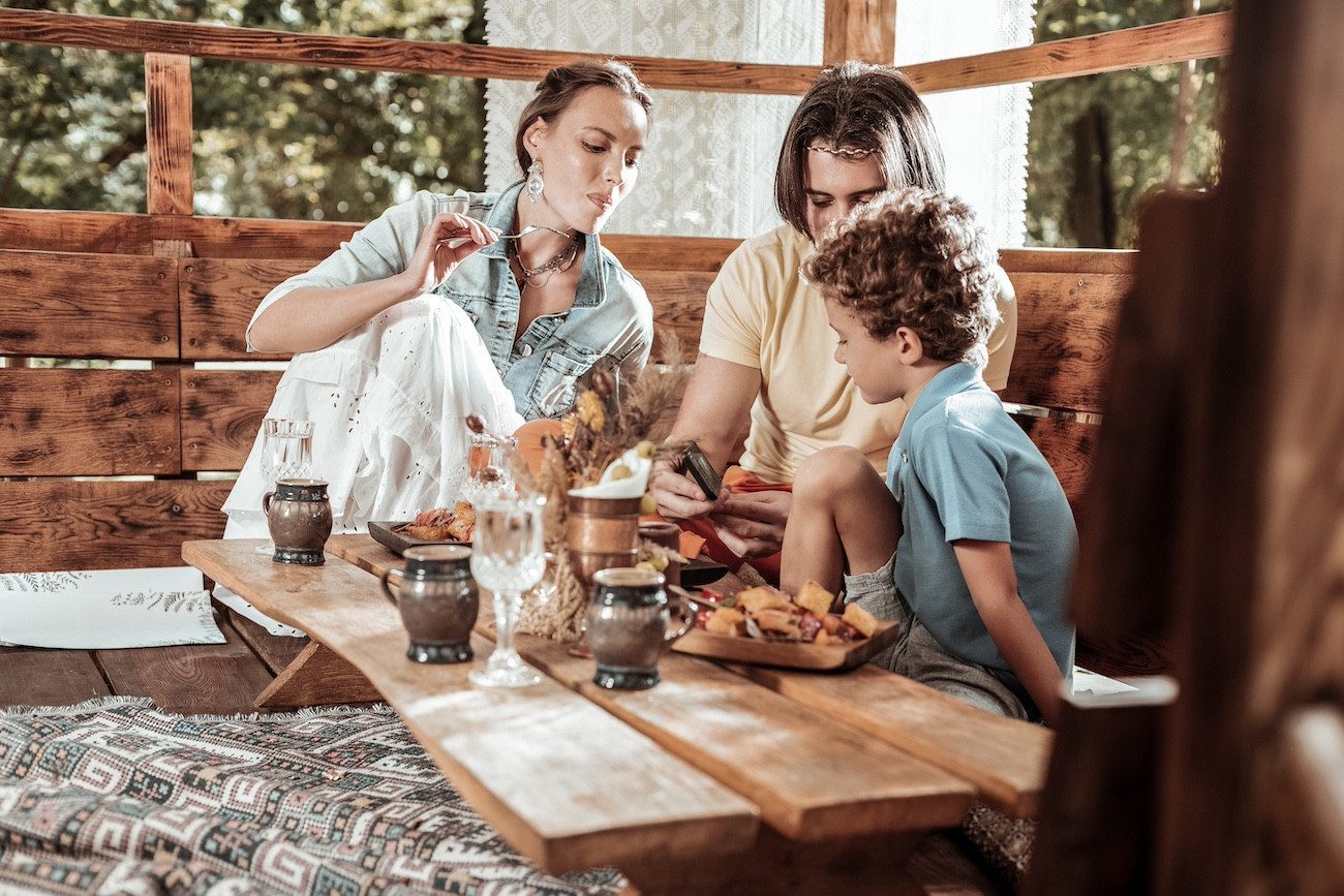 Modern technologies. Loving pleasant family having fun at the table watching something at the smartphone