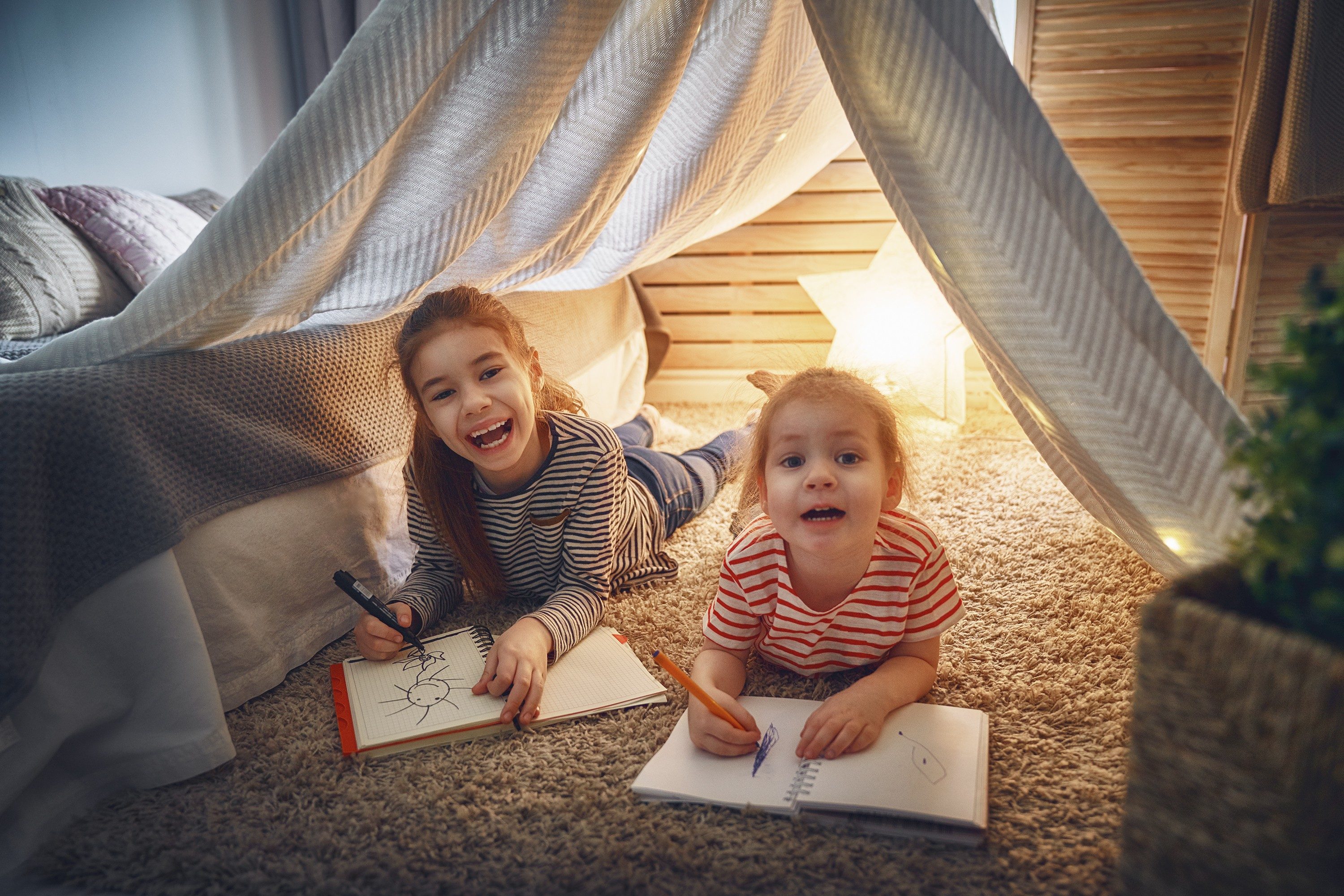 Happy children play. Little children girls draw with colored pencils indoors. Funny lovely children having fun in children room. Sisters playing together. 