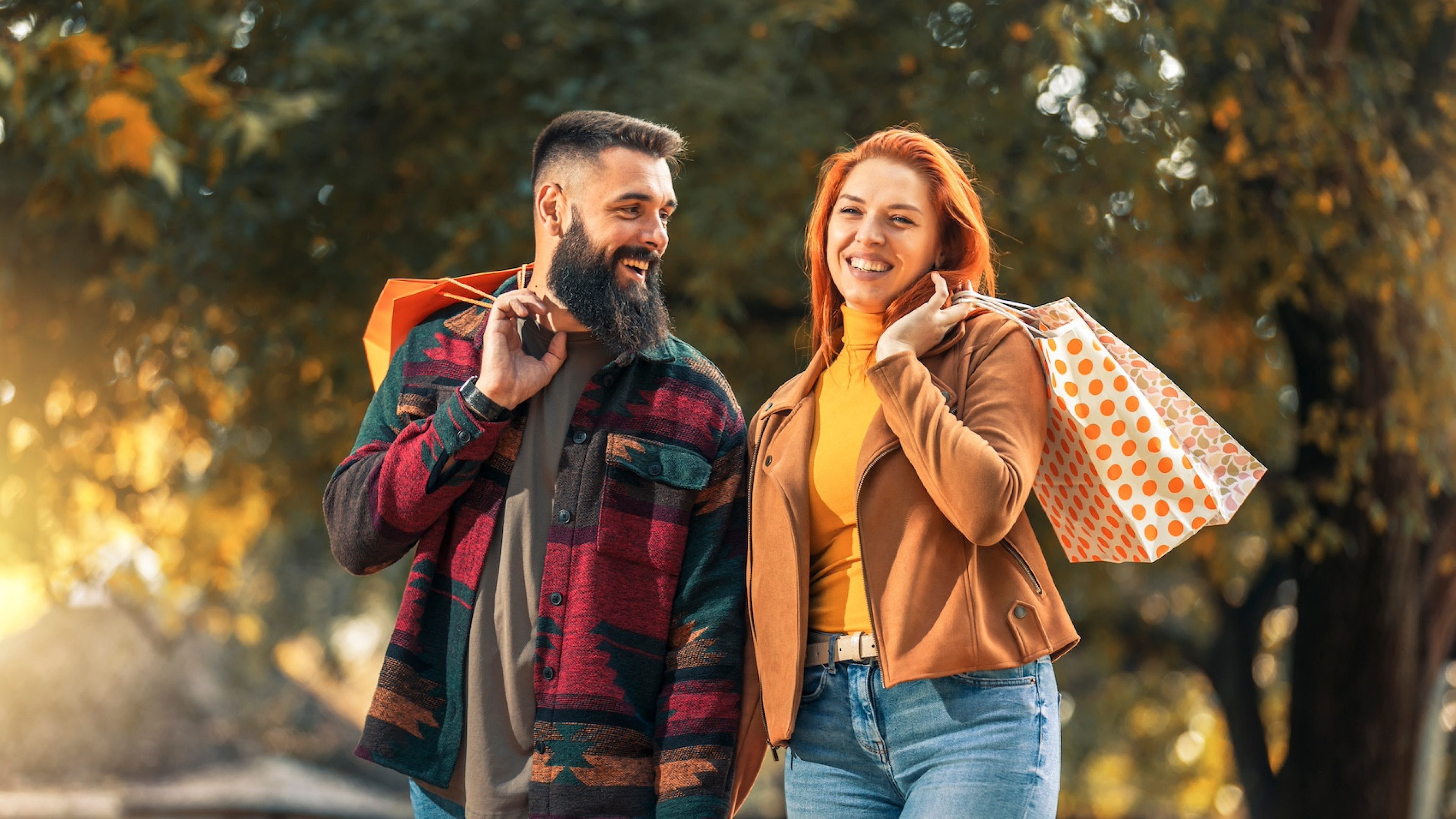 Happy couple with shopping bags in autumn park