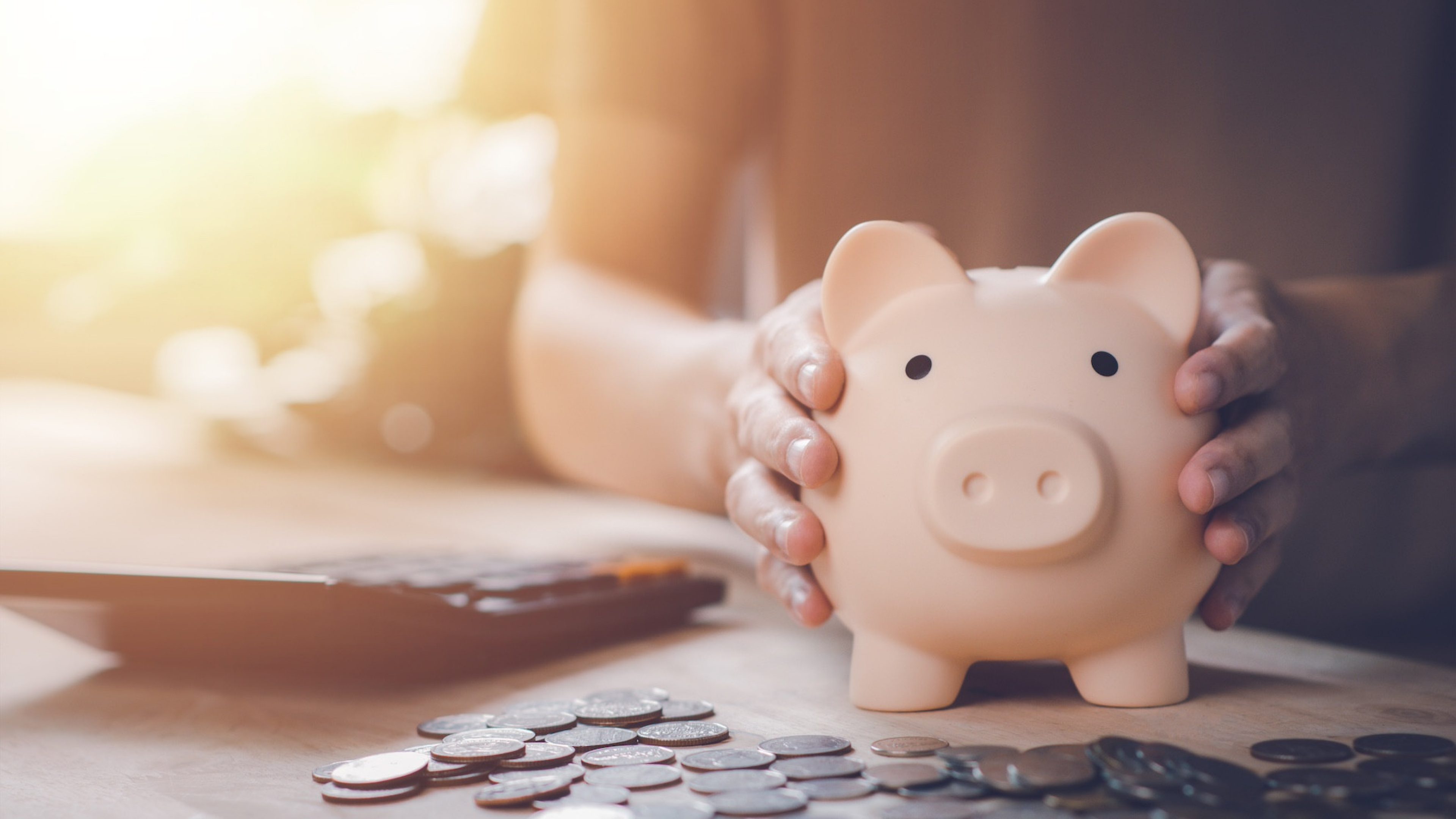 Man hand holding piggy bank with calculator and coin on wood table. Saving money wealth and financial concept. Business, finance, investment, Financial planning.