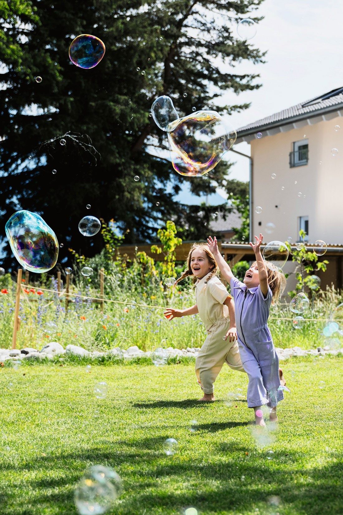 Due bambine giocano con le bolle di sapone in giardino.